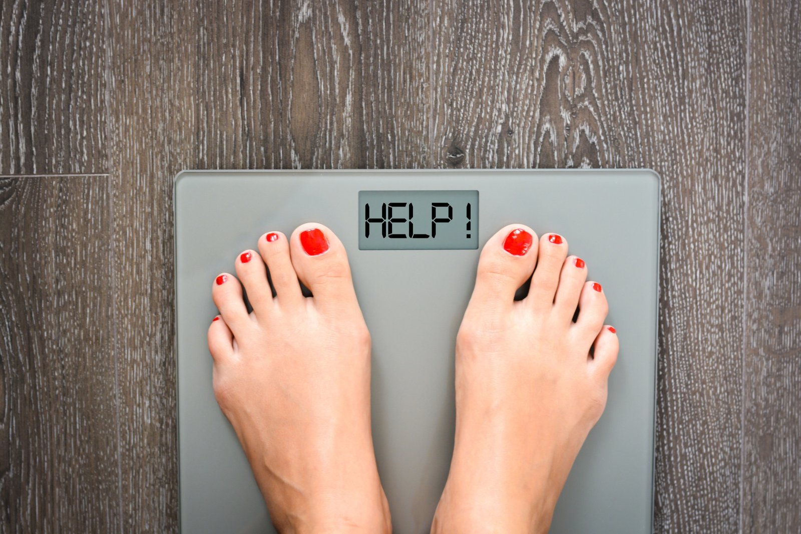 Feet on a weighing scale displaying the word 'HELP!', symbolizing weight management challenges and the need for professional support.